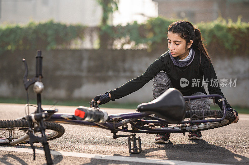 Athletic sportswoman cyclist repairing her bicycle after she fallen on road from her bicycle.